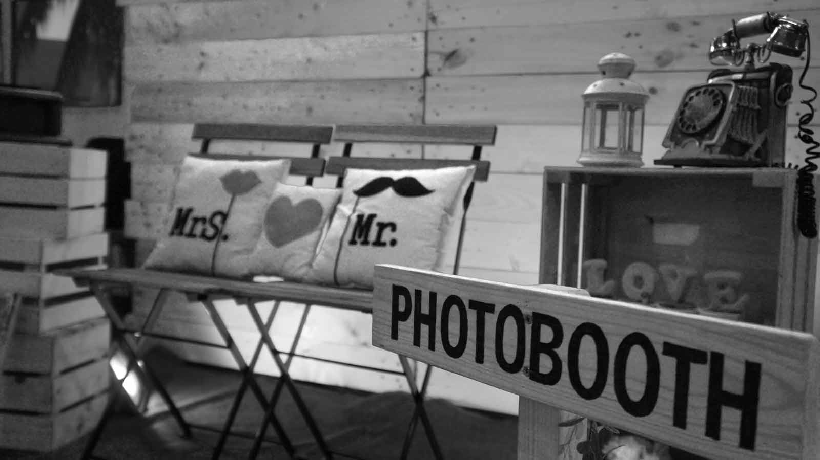 Handgeschriebenes Photobooth-Schild vor rustikaler Holzwand mit Requisiten